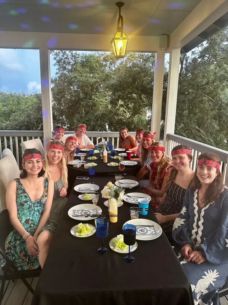 Group of people sitting at an outdoor table wearing red bandanas, enjoying a private Hibachi dinner.